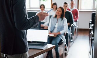 todos-estao-sorrindo-e-ouvindo-grupo-de-pessoas-em-conferencia-de-negocios-em-sala-de-aula-moderna-durante-o-dia-scaled